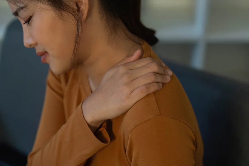woman experiences pain rubbing her shoulder
